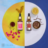 Day & Night Face Oil Duo, moisturizers for healthy skin by iYURA: the 1 fl oz (30 ml) Kesaradi Oil and Manjish Glow Elixir dropper bottles on a circle split into a yellow half, with turmeric roots, saffron and rose petals, and a white half, with half a lemon and a bowl of dried red roots, on a blue background with the iYURA logo