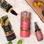 Black Gram Face & Body Duo: the Balaayah Black Gram Body Booster bottle and tube and the Yauvari Amplified Youth Spring tube and bottle on a white fluffy rug, beside turmeric root and black gram on a wooden board